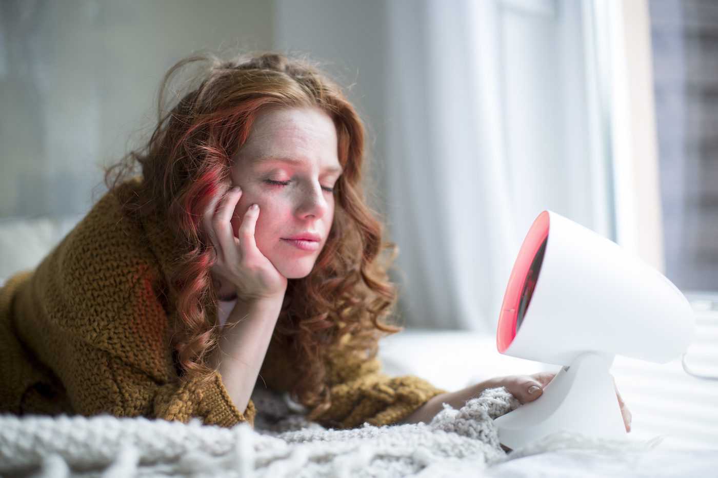 Woman lying on bed with red light therapy
