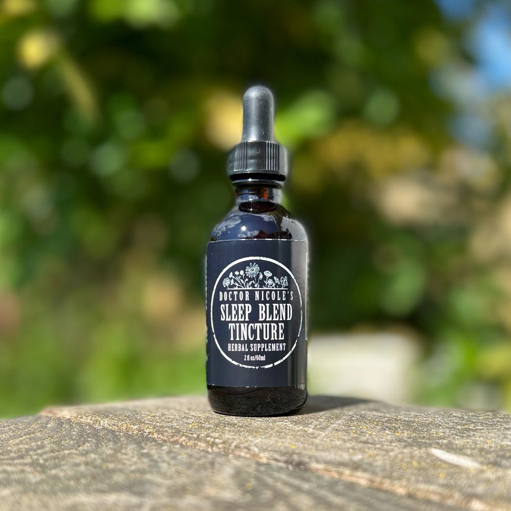 Nicoles Apothecary Sleep Blend Tincture outdoors on rustic table Nicoles Apothecary Sleep Blend Tincture outdoors on rustic table