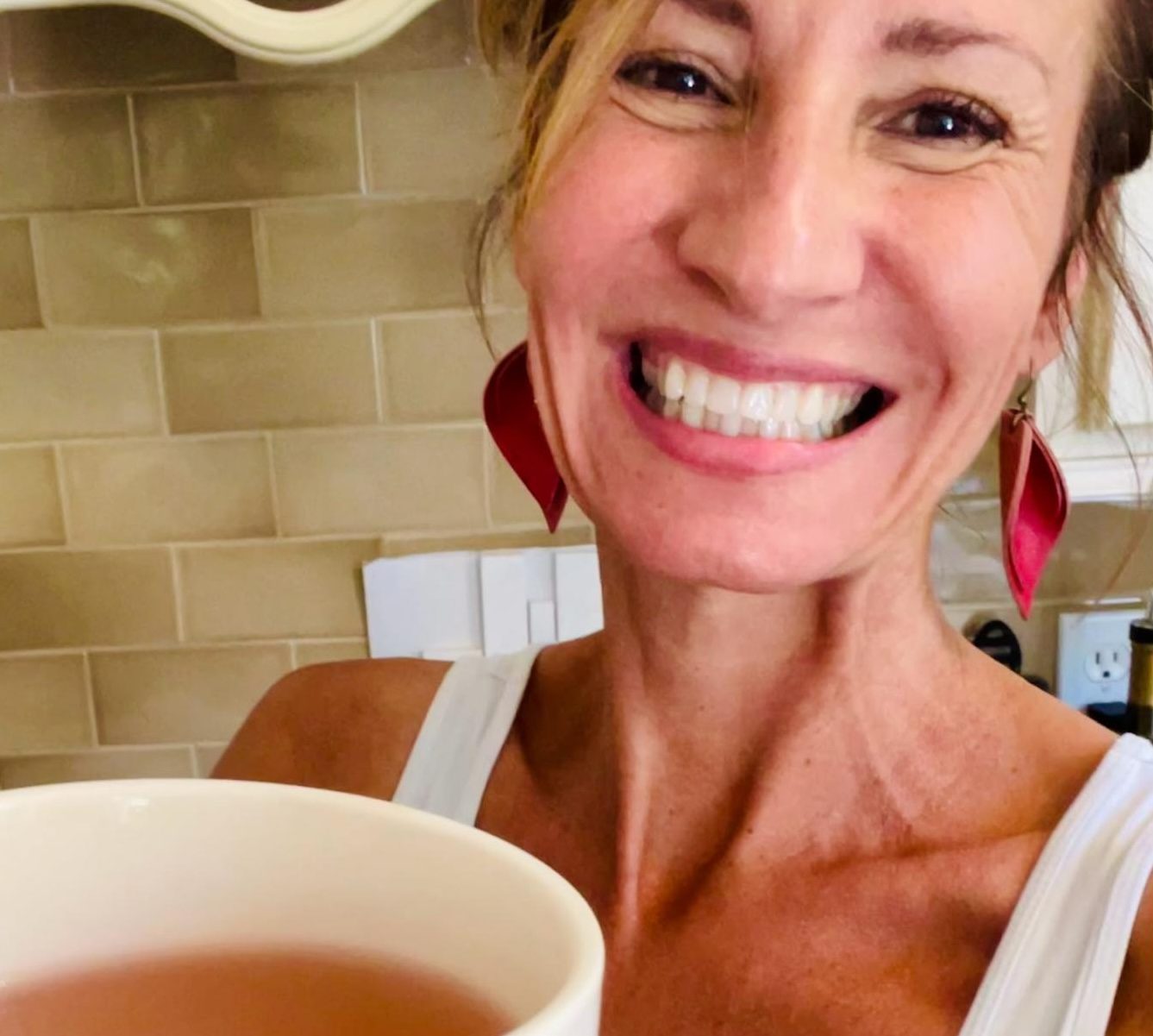 Nicole Apelian smiling and holding a mug of herbal tea